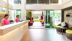 Un área de recepción con mostrador de mármol, mobiliario de mimbre y vistas al exterior.