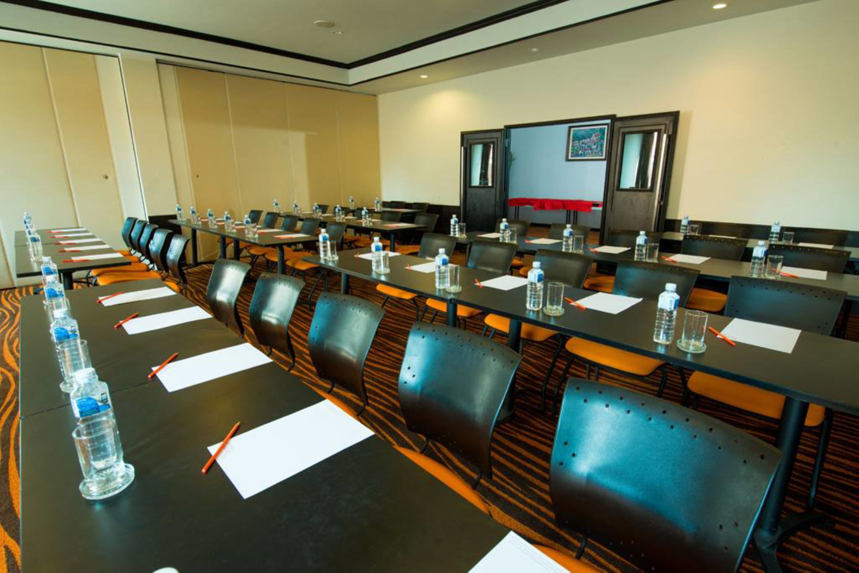 A conference room with long tables, chairs, water bottles, and papers.