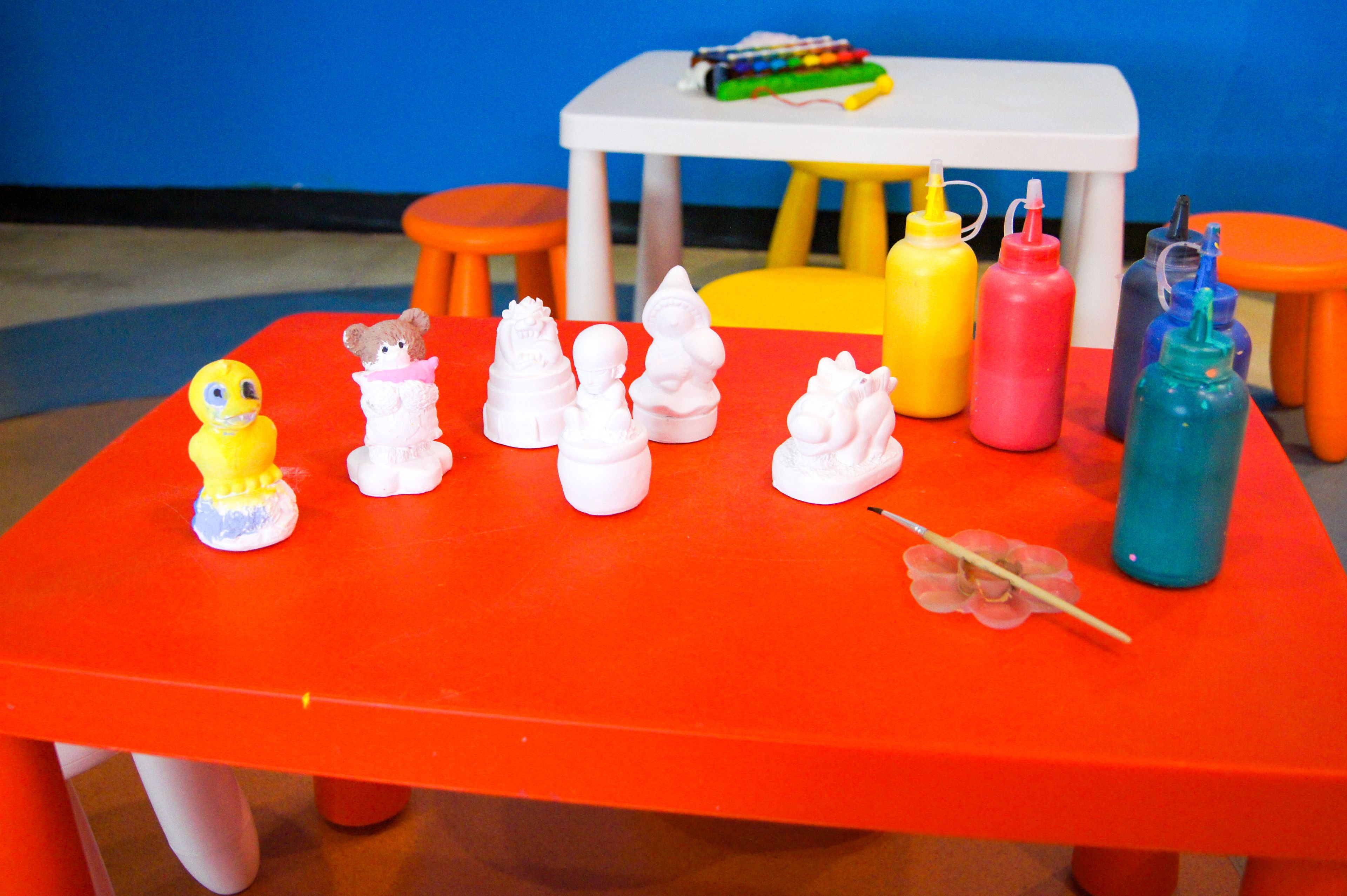 A red table with white and yellow toy figures, a blue bottle, and a toy wand.
