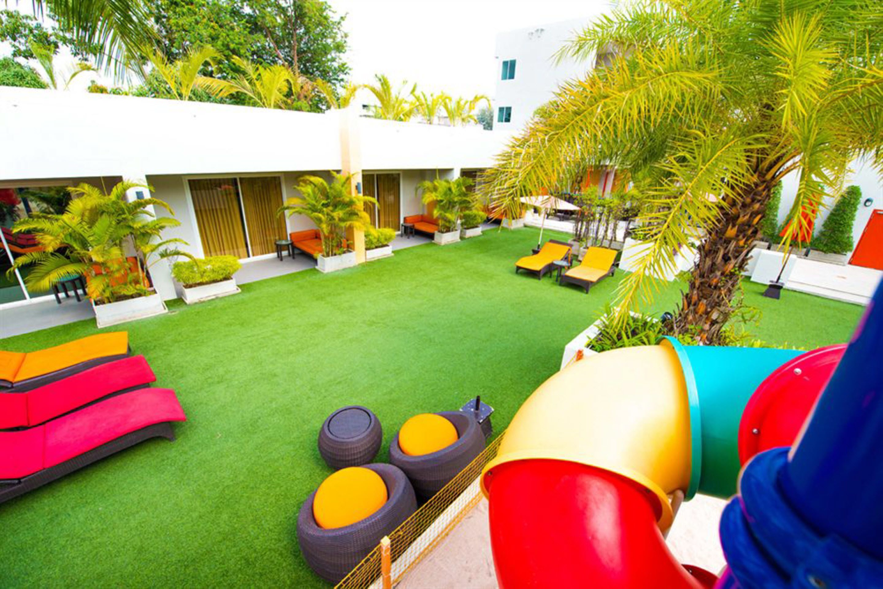 A courtyard with artificial grass, outdoor seating, and palm trees.