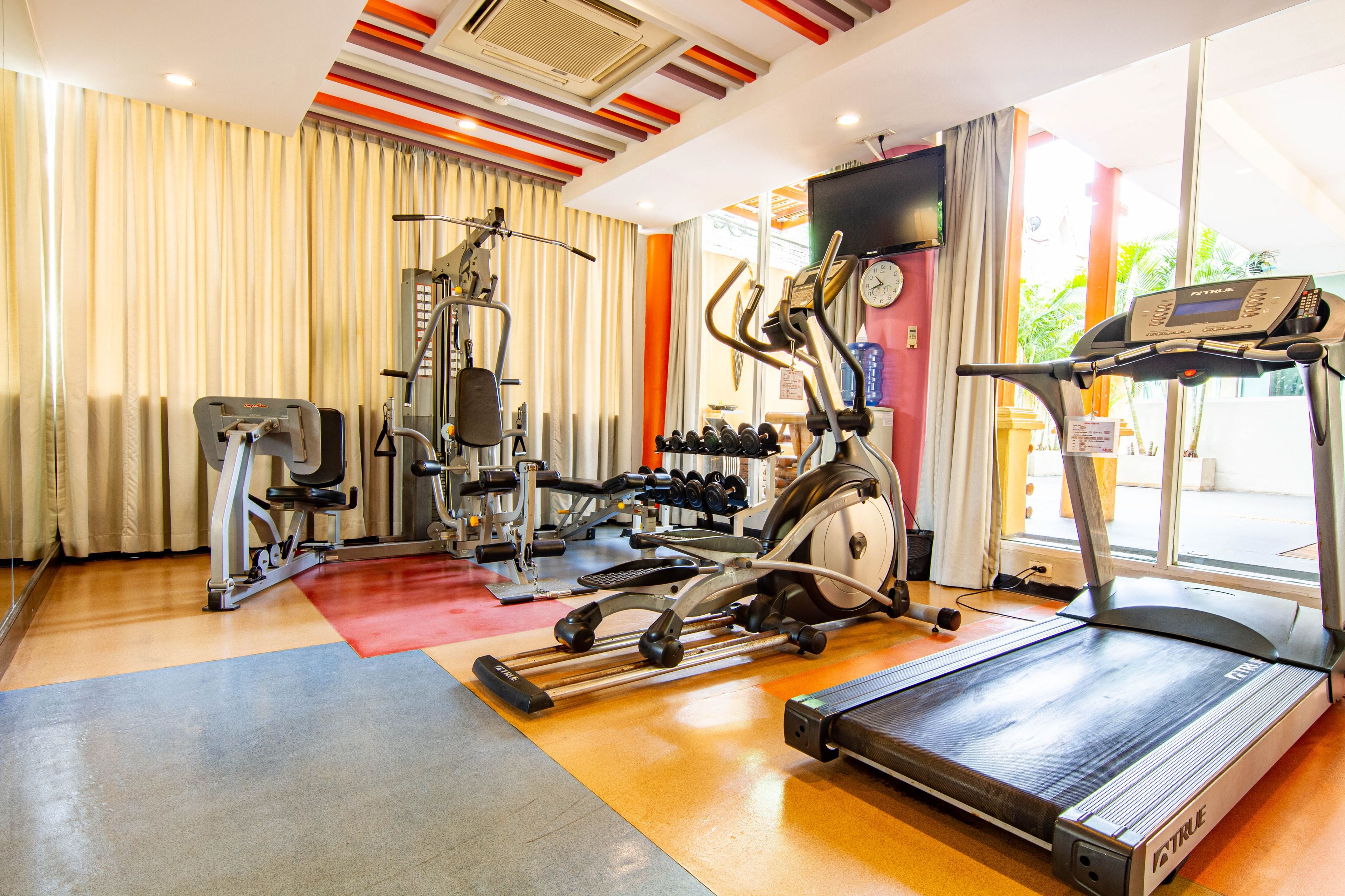 A gym with various exercise equipment including a treadmill, elliptical, and weight machines.