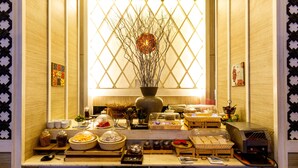 Montaje de bufé con diversos alimentos y un jarrón decorativo en el centro.