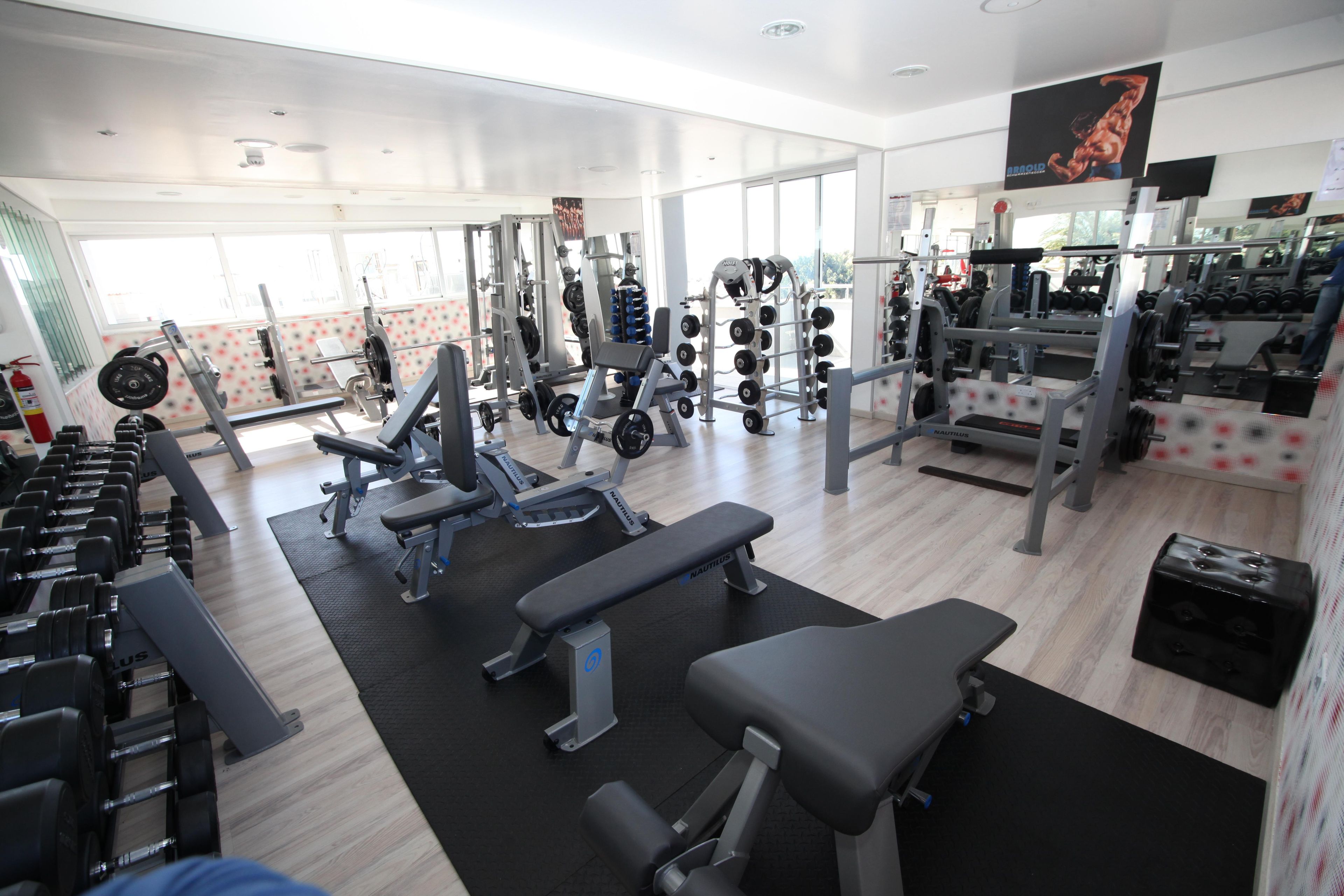 A gym with various exercise equipment, including dumbbells, weight machines, and benches.