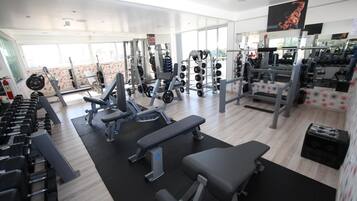 A gym with various exercise equipment, including dumbbells, weight machines, and benches.