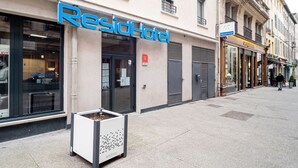 Un hotel llamado ResidHotel con una fachada moderna, ventanas amplias y una entrada visible.