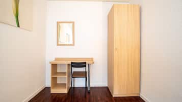 A small, well-lit room with a wooden desk, a chair, and a large wardrobe.