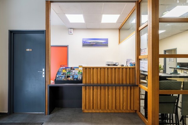 A reception area with a wooden desk, a computer, and a framed picture on the wall.