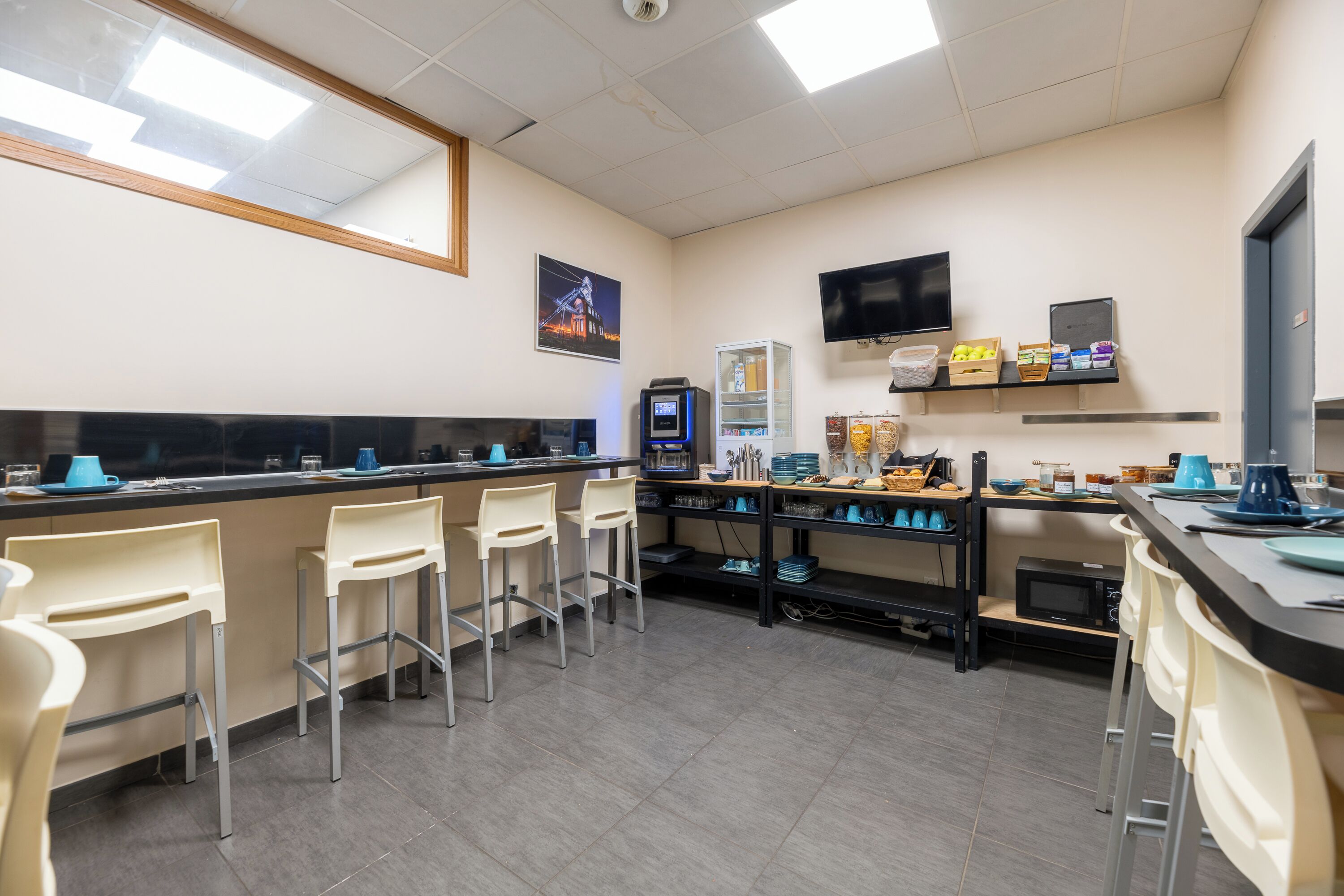 Une cuisine moderne avec un coin bar, un four à micro-ondes et un téléviseur à écran plat.