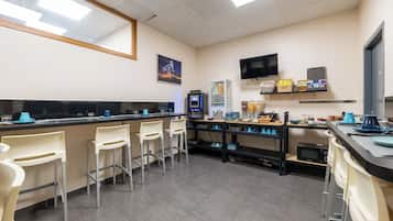 Une cuisine moderne avec un coin bar, un four à micro-ondes et un téléviseur à écran plat.
