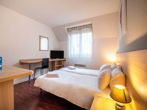 Habitación de hotel con dos camas, un escritorio, una silla, un televisor y una ventana con cortinas.