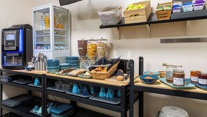 Un área de cocina con una cafetera, estantes con alimentos y diferentes utensilios de cocina.