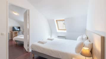 Un dormitori modern amb un llit gran, una làmpada de nit, una televisió i un fanal.