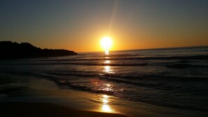 A sunset over the ocean with waves reflecting the sunlight. - Hotel Sant Jordi (Tarragona)