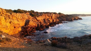 Paesaggio costiero con scogliere rocciose e vista aperta sul mare.