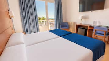 Une chambre d’hôtel avec deux lits, un bureau, une chaise, une télévision et une vue sur la mer.