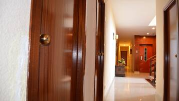 A hallway with wooden doors, a staircase, and a well-lit interior.