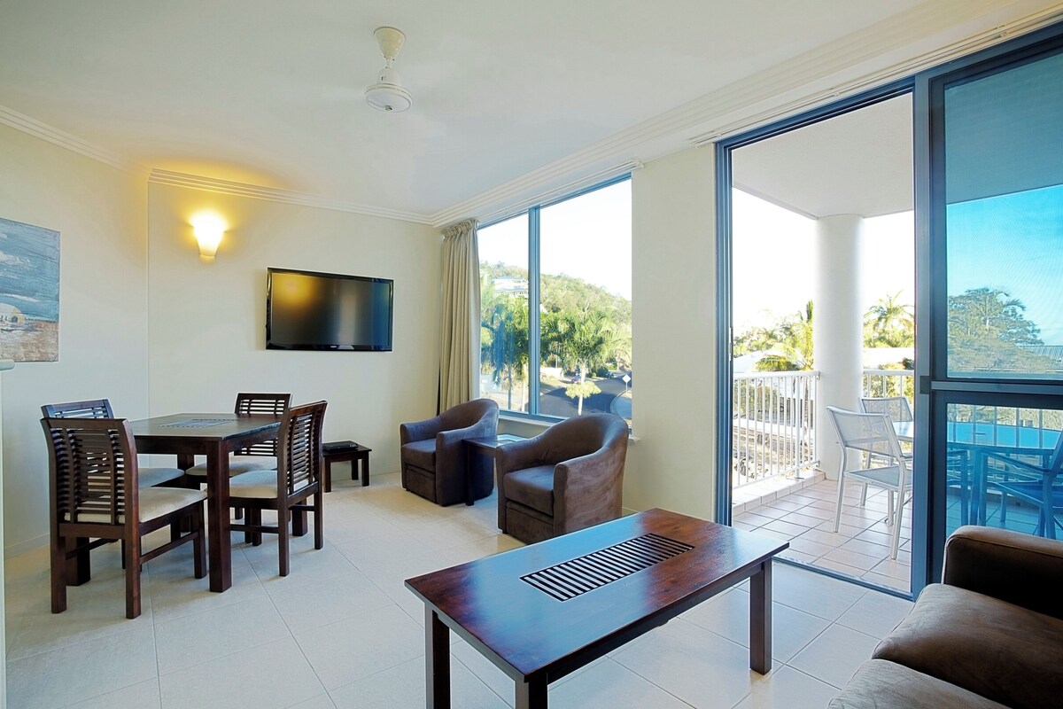 A spacious room with a dining area, a sofa, and a balcony with outdoor seating.