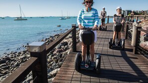 A wooden boardwalk by the sea with people riding segways. - at Whitsunday Vista Holiday Apartments (Airlie Beach)