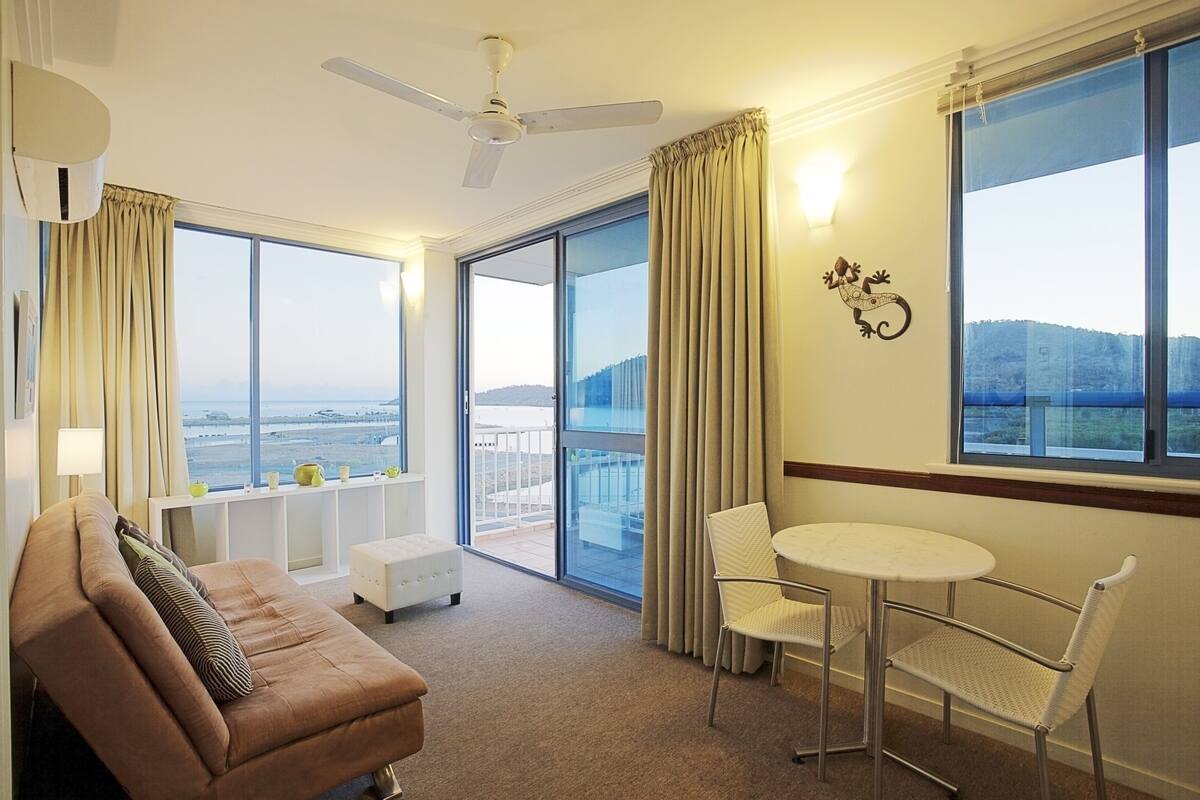 A hotel room with a large balcony, a sofa, a small table, and chairs.