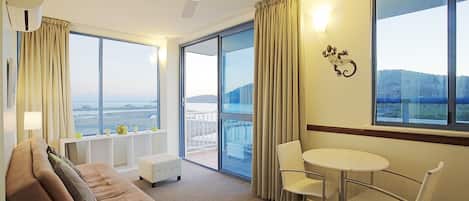 A hotel room with a large balcony, a sofa, a small table, and chairs.