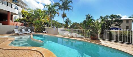 Una piscina al aire libre, sombrillas, sillones reclinables de piscina