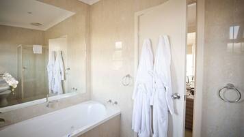 A modern bathroom with a large bathtub, a mirror, and two white towels hanging on a towel rack.