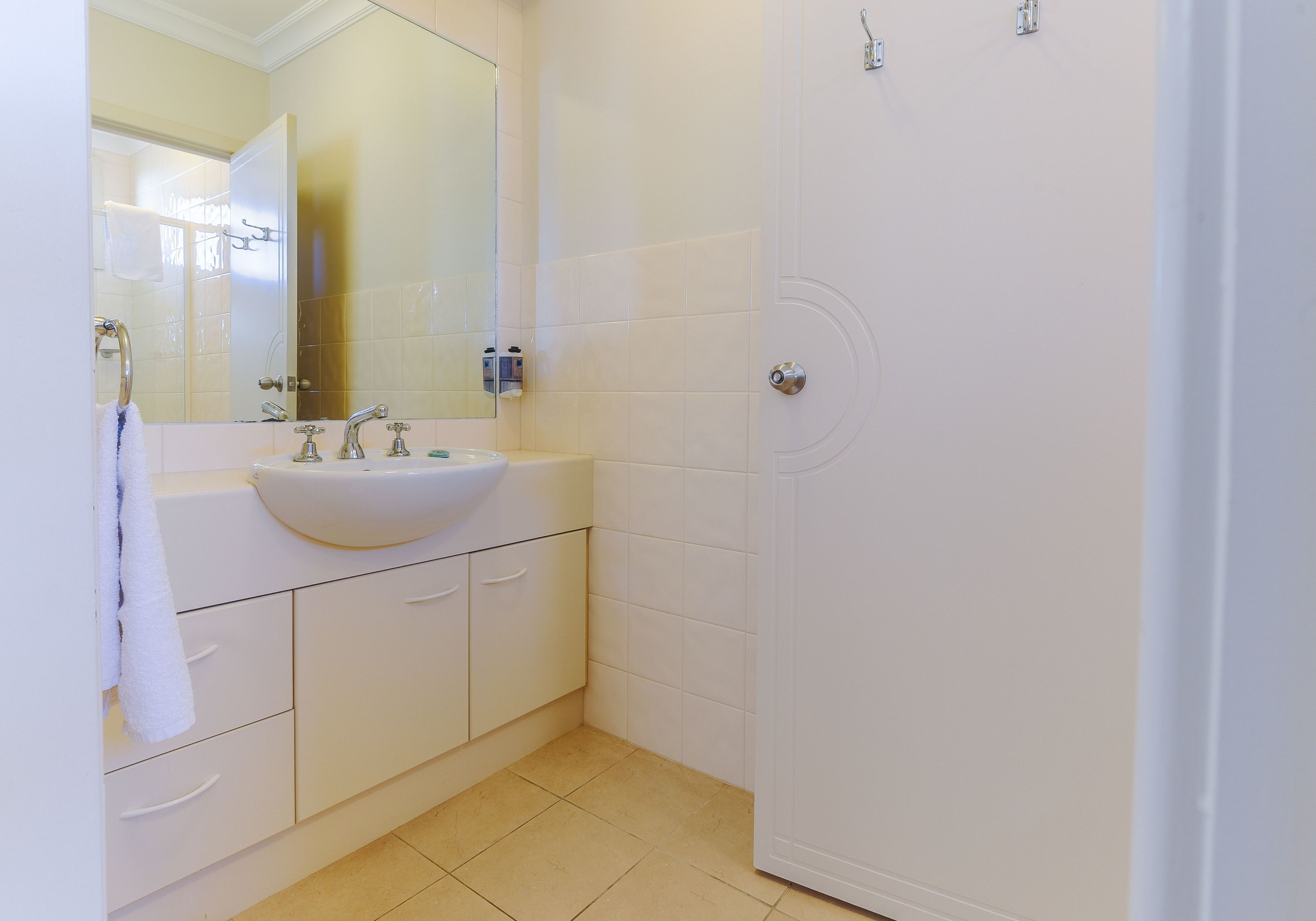 A bathroom with a white sink, mirror, and tiled walls.