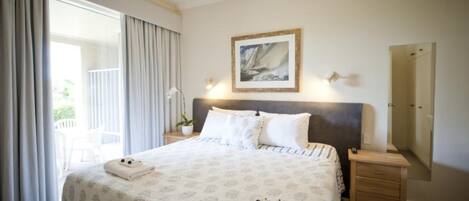 A hotel room with a bed, a nightstand, a bedside table, a mirror, and a window with curtains.