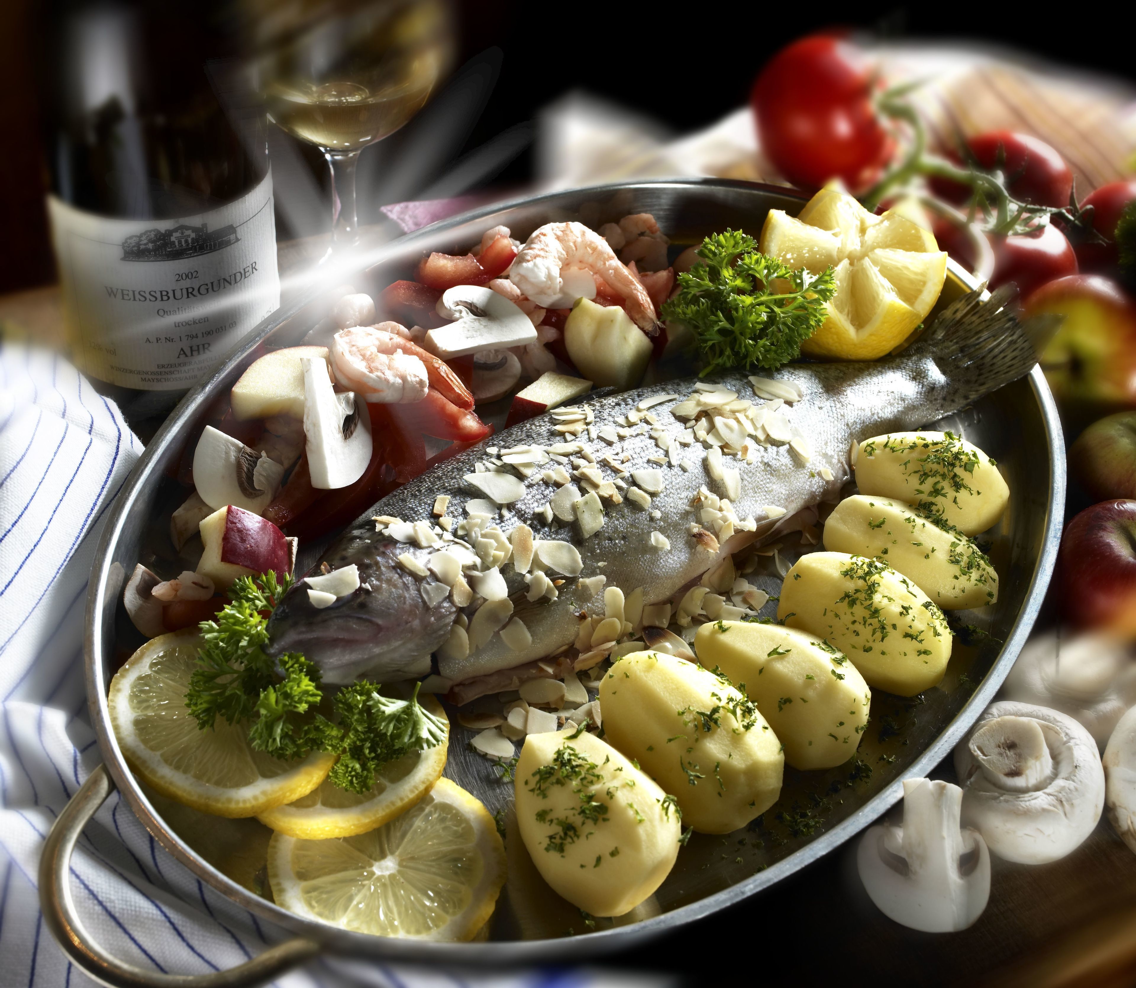Un plato con pescado, papas y verduras.