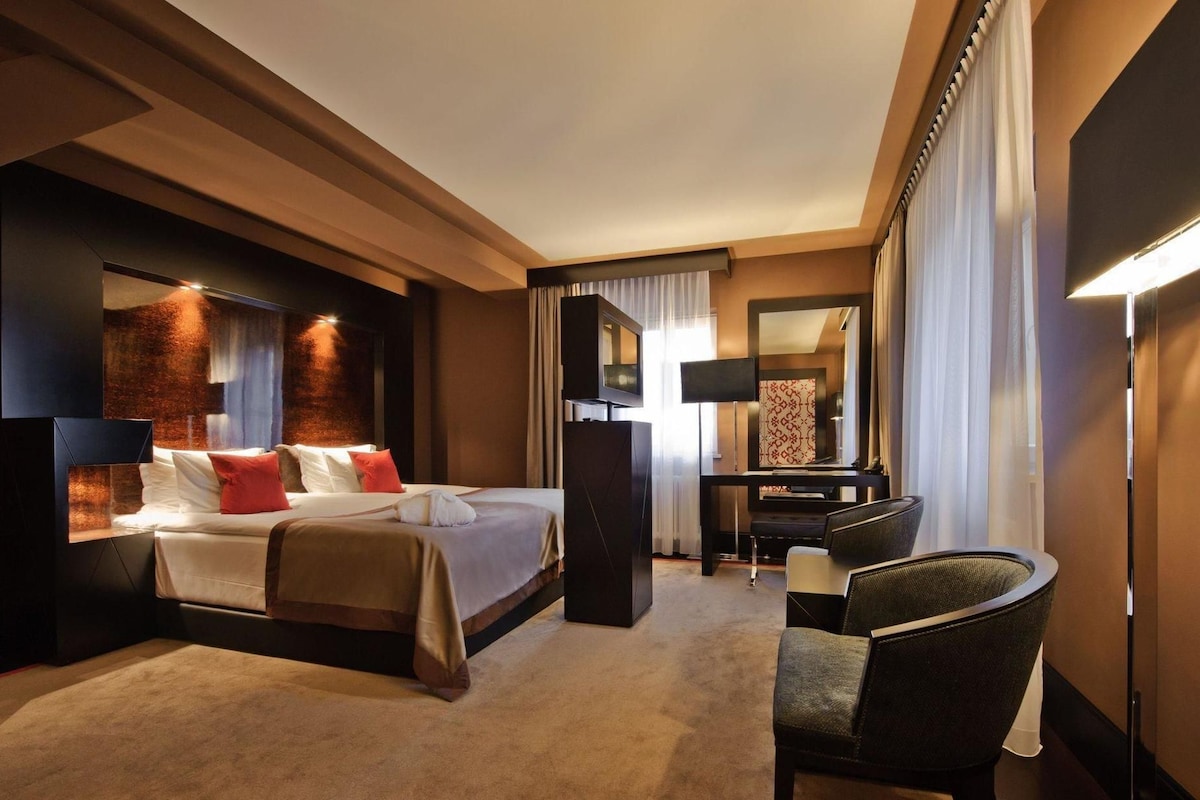 A hotel room with a bed, a desk, a chair, a television, and a mirror.