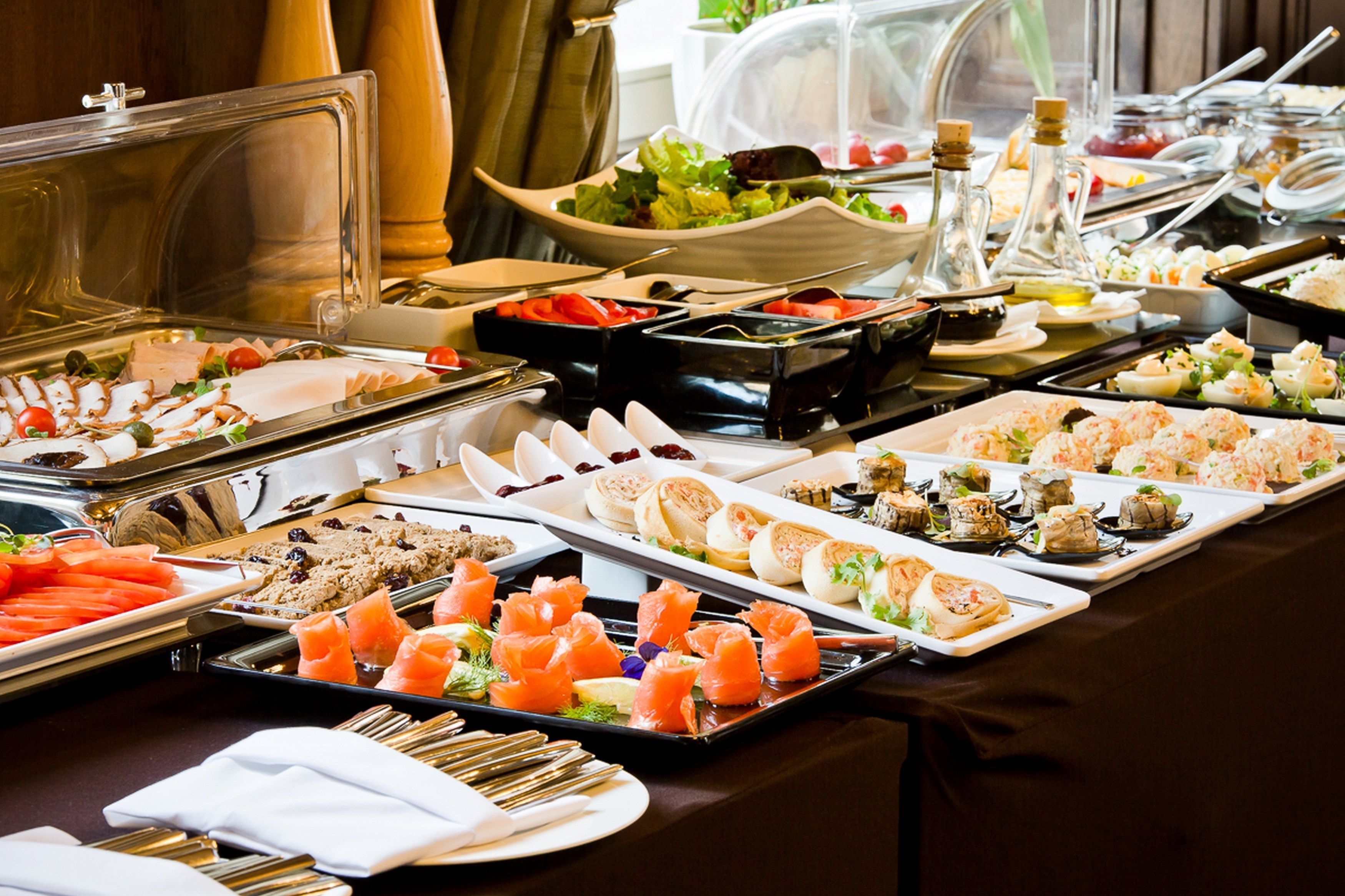 Un buffet con diverse pietanze, tra cui salmone, insalate e pasticceria.