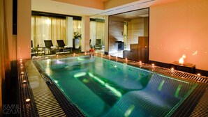 A large indoor swimming pool with a tiled floor, surrounded by lounge chairs and a seating area with curtains. - Platinum Palace Boutique Hotel & SPA (Wroclaw)