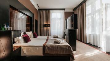Una habitación de hotel moderna con dos camas, un televisor de pantalla plana, un minibar y ventanas amplias con cortinas translúcidas.