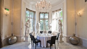 A formal dining room with a round table, chairs, a chandelier, and statues. - Platinum Palace Boutique Hotel & SPA (Wroclaw)