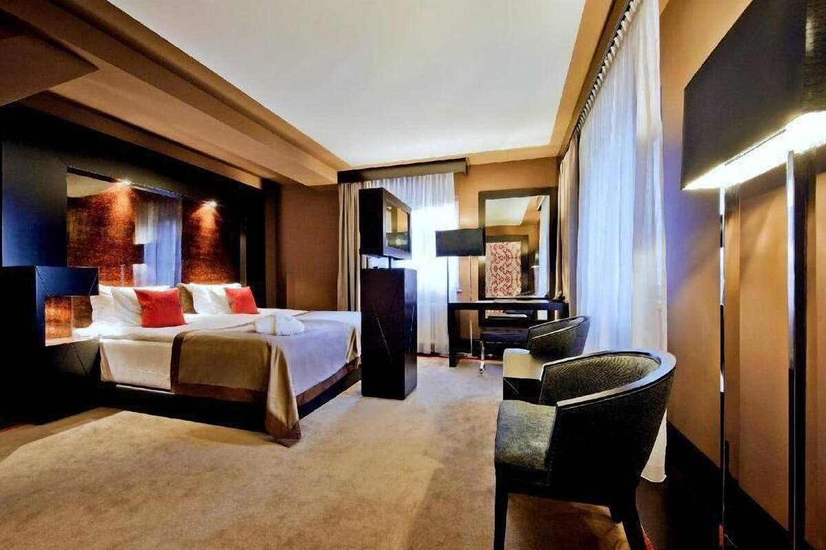 Ein Hotelzimmer mit einem großen Bett, einem Schreibtisch, einem Sessel und einem Spiegel.