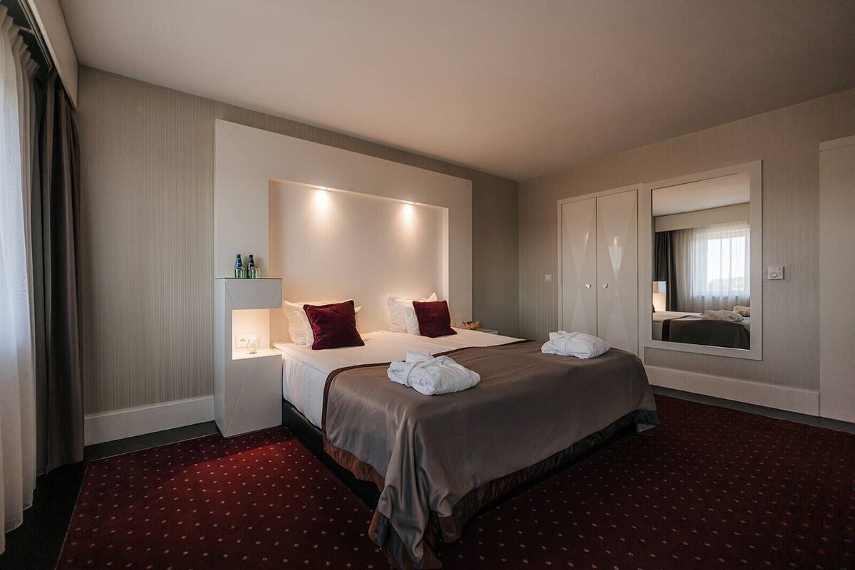 Ein Hotelzimmer mit einem großen Bett, einem Nachttisch, einem Kleiderschrank und einem Spiegel.