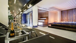 A modern hotel lobby with a reception desk, a bar area with a bottle of champagne and glasses, and a decorative light display. - Platinum Palace Boutique Hotel & SPA (Wroclaw)