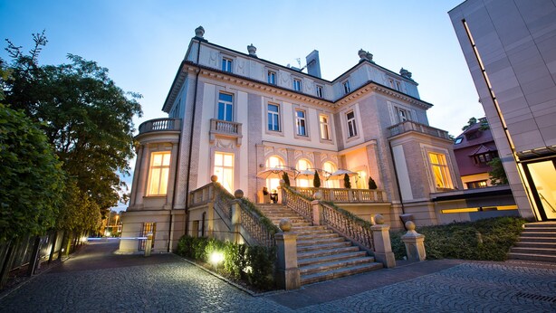 A historic building with a grand staircase, multiple windows, and a well-lit entrance. - Platinum Palace Boutique Hotel & SPA (Wroclaw)