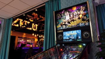 Zona de bar com sinalização iluminada e uma tela grande exibindo um jogo.