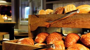 A wooden display case with various baked goods, including croissants and bread, in a bakery setting.