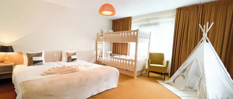 Habitación de hotel con literas, un sofá, un tipi y una lámpara.