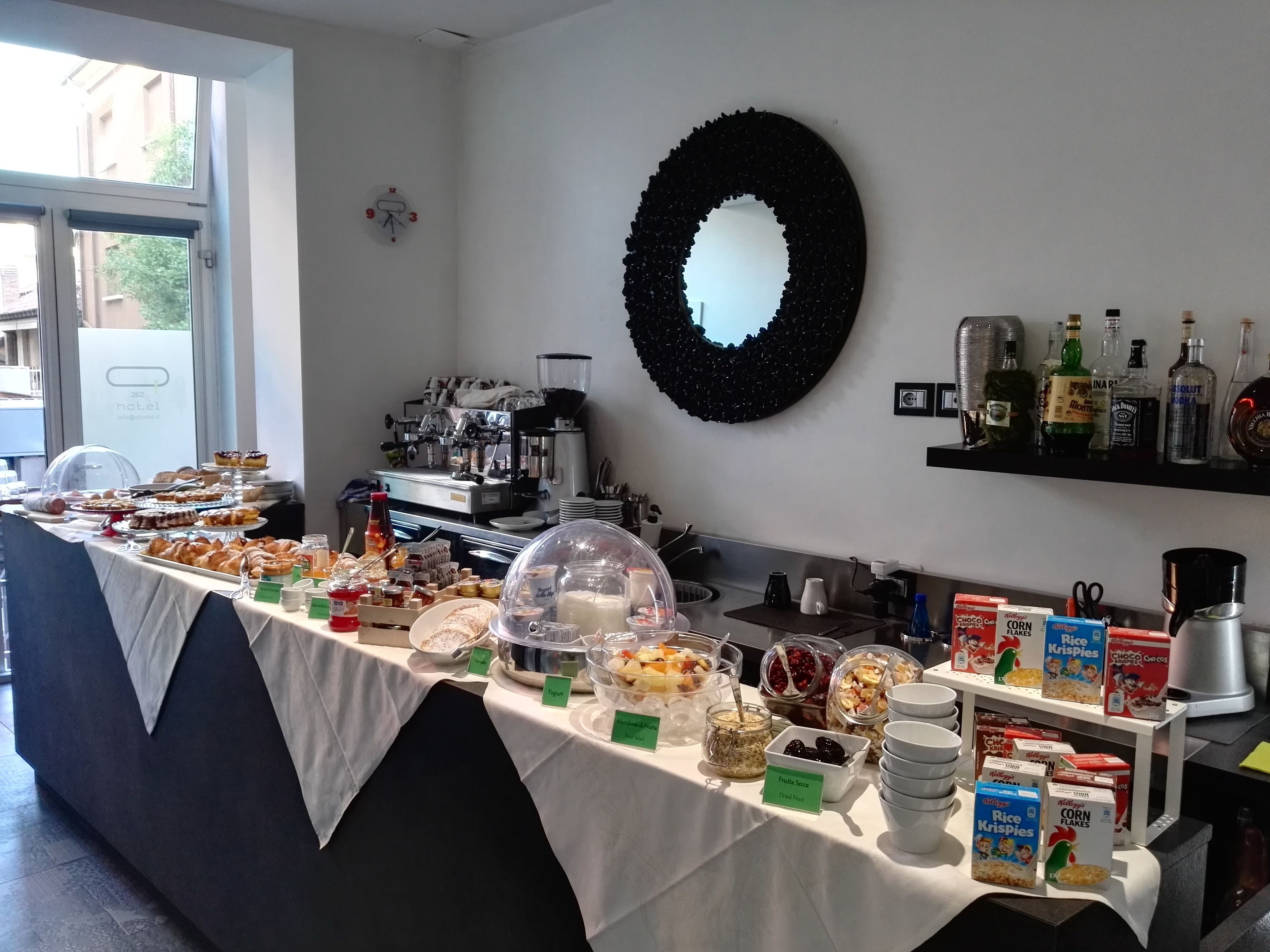 A buffet with various food items, a coffee machine, and a mirror on the wall.