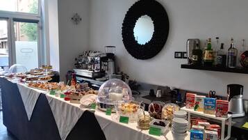 A buffet with various food items, a coffee machine, and a mirror on the wall.