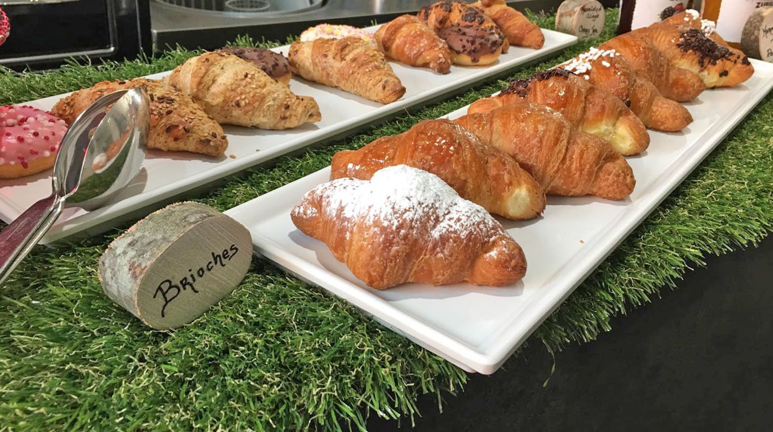 A variety of pastries on a white plate with a label "Brioche" on a wooden block.