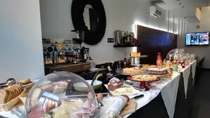 A buffet setup with various food items, including meats, cheeses, and pastries, arranged on a table with a white tablecloth. - Q Hotel (Rimini)