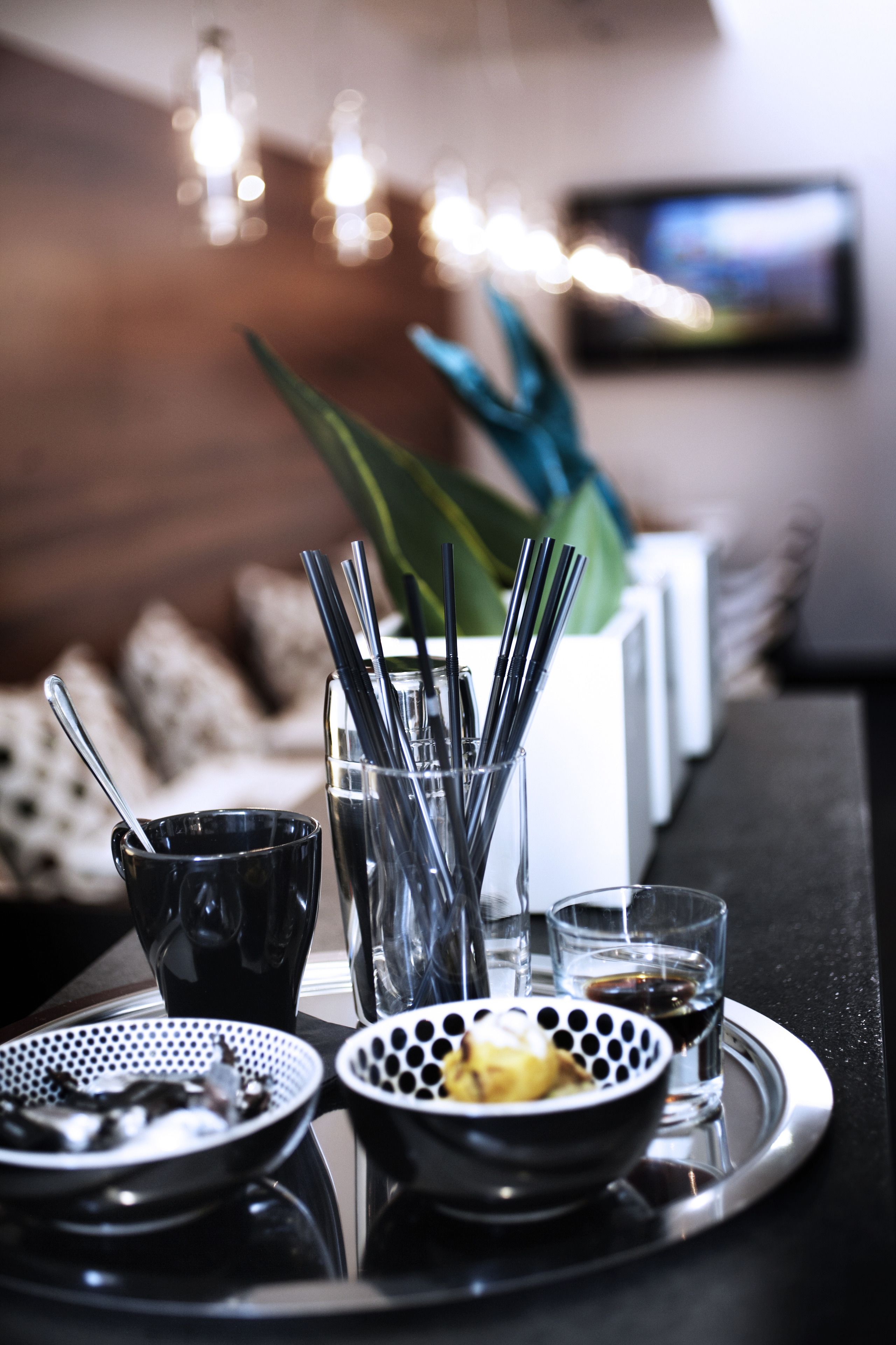 A tray with a bowl of food, a glass of water, and a glass of dark liquid, possibly coffee, on a table with a modern design.