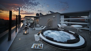 A rooftop deck with a hot tub, lounge chairs, and a table with snacks. - Q Hotel (Rimini)