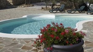 A swimming pool with lounge chairs, a stone patio, and a castle in the background. - Relais Colline San Biagio (Carmignano)