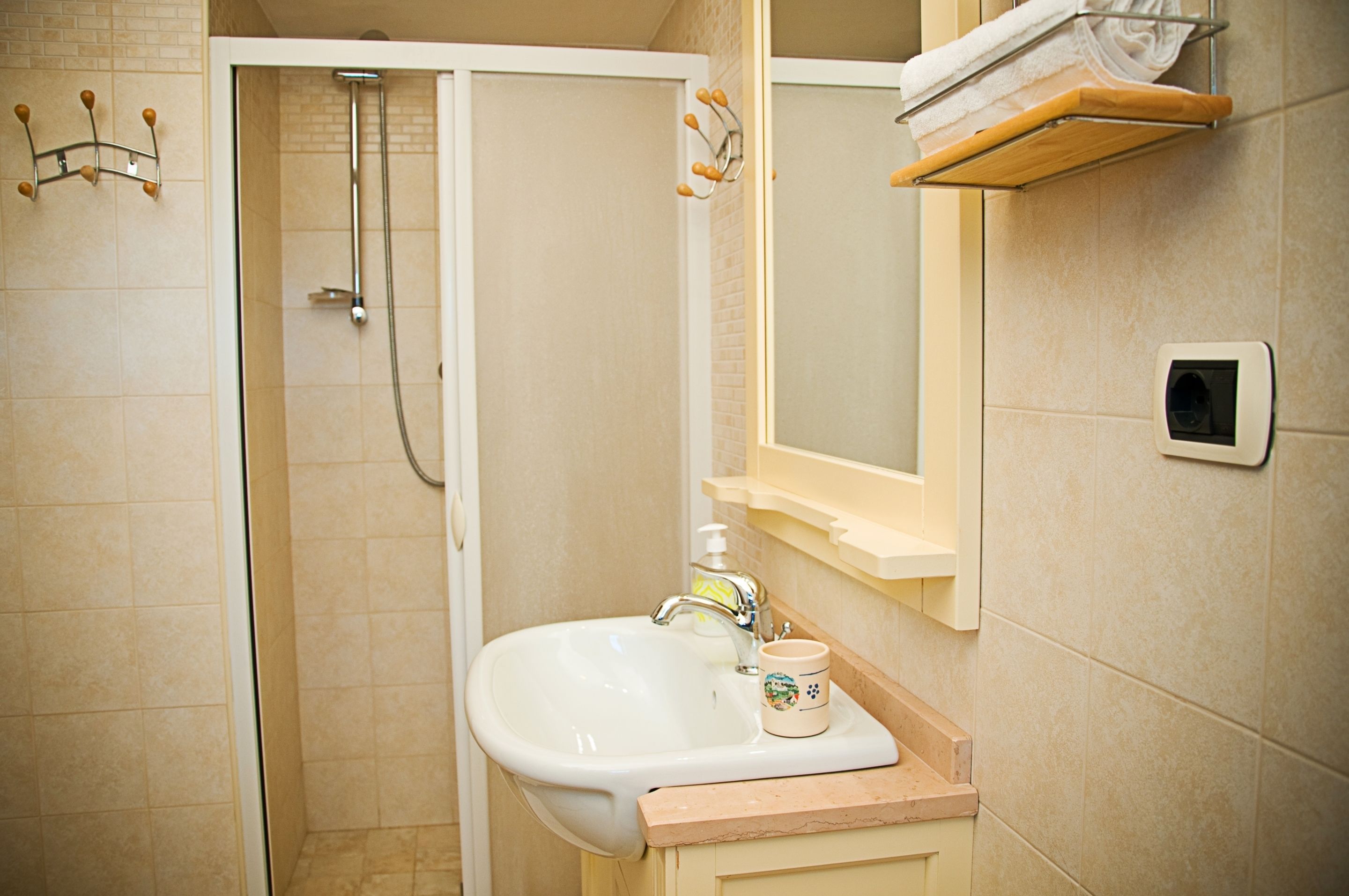 Un baño con ducha, lavabo y perchero para toallas.