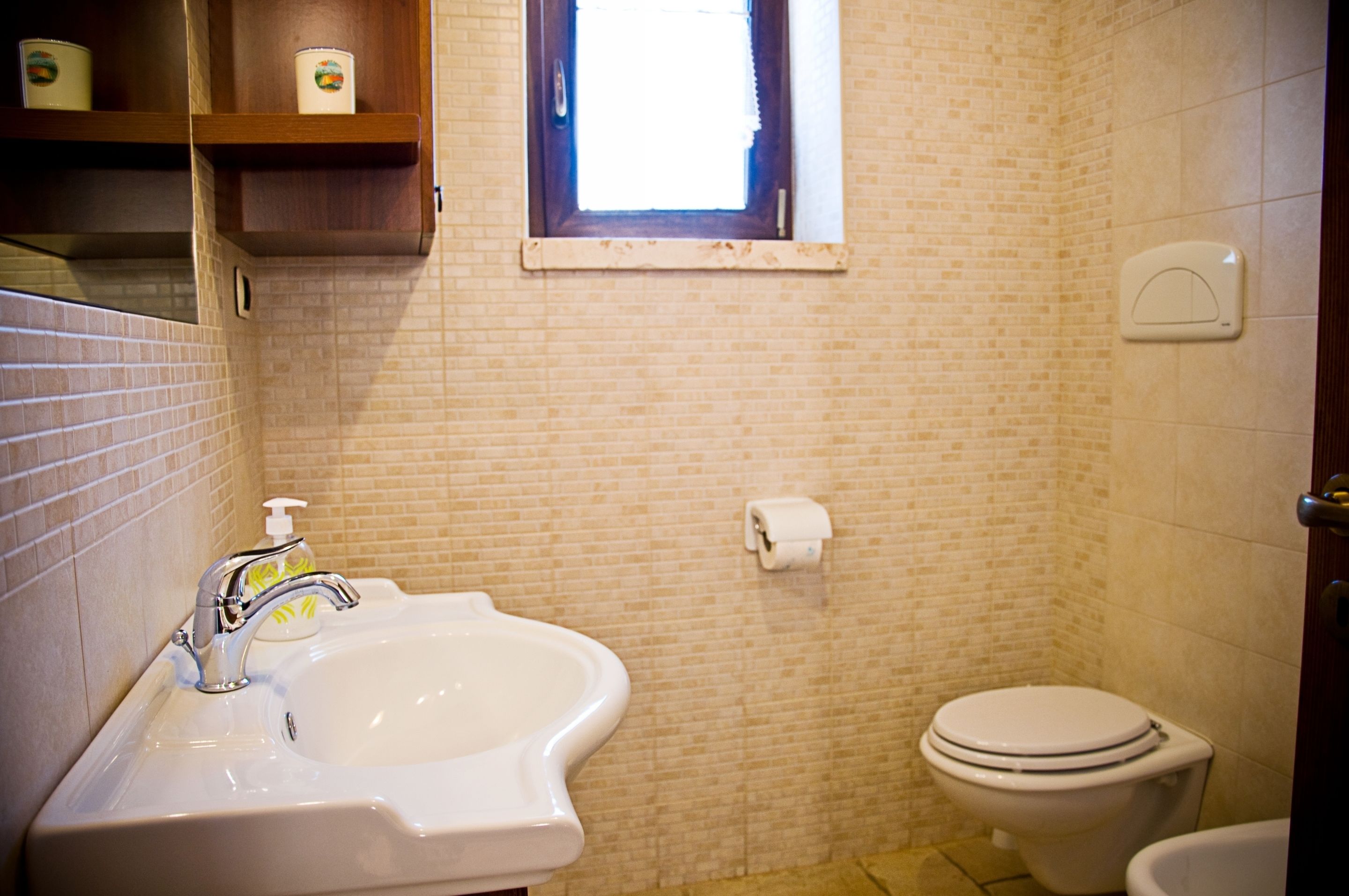 Un baño con lavamanos, inodoro y ventana.